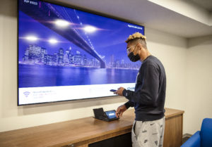 UMW student Wilson Jackson, a junior marketing major and resident assistant, tries out a huge TV in the newly constructed basement lounge with full-size kitchen. Spaces like these allow students to connect and build friendships. Photo by Tom Rothenberg.