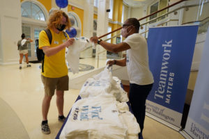 Orientation Coordinator Joey Zeldin grabs a "Find What Matters" T-shirt from Director of University Marketing Malcolm Holmes in the University Center. Photo by Suzanne Carr Rossi.
