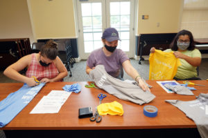 From left to right, Catherine DeGoyler, Julia Hoffman and Purnaja Poddurturi make reusable grocery bags out of old COAR T-shirts for the Fredericksburg Food Co-op. Photo by Suzanne Carr Rossi.