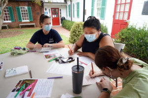 From left to right, Abigail Wood, Ashleigh Liang Foster and Mallory Karnei write notes to servicemembers, military families and local veterans at the James Monroe Museum. Photo by Suzanne Carr Rossi.