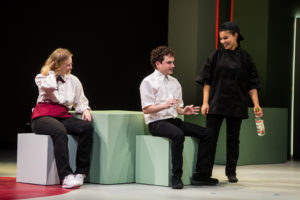 Oscar León (center) as George talks to the crew, including Shannon Hardy (L) and Maddie Baylor, during a smoke break at Kenny’s restaurant. Photo by Geoff Greene.