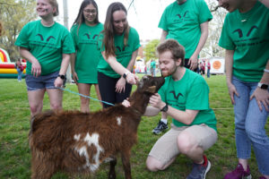 David Stout pets Cupid the Goat while his fellow UMW Goats look on. Photo by Suzanne Carr Rossi.