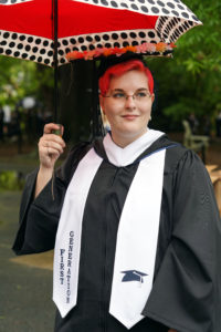 A first-generation UMW graduate shields her graduation cap from the rain at the 2022 Commencement ceremony. Photo by Suzanne Carr Rossi.