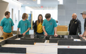 Colonial Beach Mayor Robin Schick visits the Colonial Beach High School robotics team as they run their robot through a practice course during the second day of the High School Innovation Challenge @ Dahlgren. (U.S. Navy photo/Released)