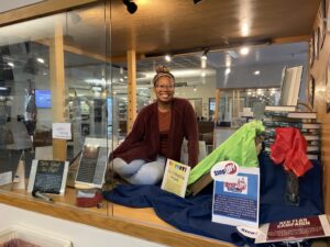 Center for Prevention and Education Director Marissa Miller strikes a fun pose inside one of the two Simpson Library display cases now filled with memorabilia to recognize the 50-year anniversary of Title IX. "We must remember the other side of compliance," Miller said, "including prevention, education and advocacy.