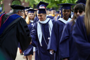 Faculty members line up on either side of Campus Walk to cheer on the graduates. Photo by Suzanne Carr Rossi.