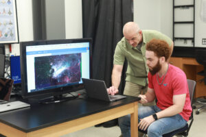 Professor of Physics Matthew Fleenor (left) works with UMW senior Jason Walker during the Summer Science Institute. Walker is using capabilities like narrowband imaging and mosaicking to better understand the environments where stars are currently forming. Photo by Karen Pearlman.