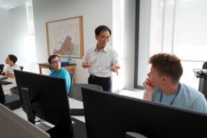 Associate Professors of Computer Science Xin-Wen Wu (pictured here talking with Collin Nester) and Andrew Marshall co-taught "An Introduction to Cybersecurity" course during the Summer Enrichment Program. Photo by Suzanne Carr Rossi.