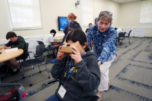 Assistant Professor of Writing Studies and Digital Studies Brenta Blevins pushes high-schooler Elyse Katolin of Crofton, Maryland, during a virtual reality experience. The exercise was part of "The Realities of Virtual Reality and Augmented Reality," a course Blevins taught during this year's Summer Enrichment Program for pre-college students. Photo by Suzanne Carr Rossi.