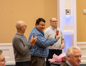 Executive Director of Alumni Engagement and Advancement Communications Mark Thaden (center) shows off the prize he won during this week's employee luncheon as UMW President Troy Paino (left) and Executive Director of Dodd Auditorium Douglas Noble (right) look on. Photo by Sam Cahill.