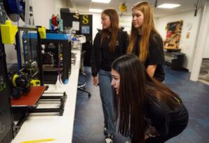 Left to right: Kayle Ramirez, Emily Harding, and Katherine Hernandez look at a 3D printer in the makerspace. Photo by Suzanne Carr Rossi.