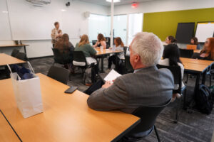 College of Education Dean Pete Kelly listens as former Peace Corps Director Jody Olsen speaks to a roomful of students about the importance of service abroad. Photo by Suzanne Carr Rossi.