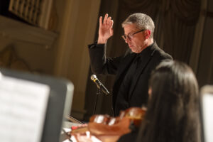 UMW Professor of Music and Director of Choral Activities Christopher Ryder conducts as an ensemble of singers and musicians converge for Sunday's rehearsal. Photo by Tom Rothenberg.