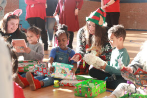 UMW junior Sarah Hybl, an English major who is also studying secondary education, helps Santa deliver a gift to a preschool student in Fredericksburg. Photo by Karen Pearlman.