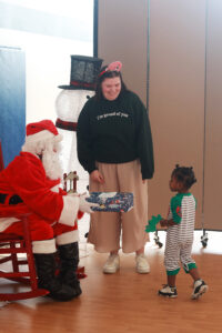 UMW junior Sarah Hybl, an English major who is also studying secondary education, helps Santa deliver a gift to a preschool student in Fredericksburg. Photo by Karen Pearlman.
