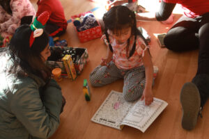 UMW senior Khushi Constance, a marketing major and COAR staff director, talks with a preschool student who's already started coloring in her new coloring book with her new crayons. Photo by Karen Pearlman.