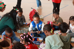 Four-year-old Jaylyn (center) checks out a set of colorful toothbrushes inside the gift box he received from UMW's COAR. For its annual gift box effort, the group filled more than 200 wrapped boxes with useful and fun items for kids. Photos by Karen Pearlman.