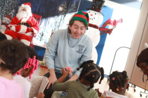 UMW sophomore Knox McKinley talks with a group of preschool students as they open gift boxes provided by UMW's COAR. Photo by Karen Pearlman.