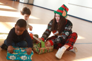 UMW sophomore Jillian Vargas, an international relations major who works handles COAR's social media, helps children unwrap and discover their gifts. Photo by Karen Pearlman.