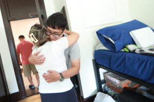 First-year UMW student Mauricio Penado hugs his mother goodbye after setting up in his Virginia Hall room. Mauricio will miss her but brought along a framed photo to keep on his desk. Photo by Karen Pearlman.
