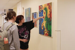 First-year students Caitlyn Faris and Morgan Hamm check out the senior studio art exhibit on the first floor of the Cedric Rucker University Center. Photo by Karen Pearlman.