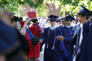 Graduates get handshakes and high-fives from faculty members lined up on either side of Campus Walk to cheer them on. Photo by Suzanne Carr Rossi.