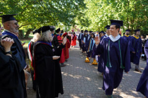 Graduates walk through campus on their way to Ball Circle for this year’s commencement ceremony, including Martina Nicholson who’s wearing the “feet” of the school’s Sammy D. Eagle mascot. Photo by Suzanne Carr Rossi.
