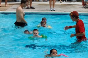 Diederich (with yellow floaties) had a longtime connection with head swim coach Justin Anderson ’10 (in red), who taught him and sister Ashlyn to swim at a young age.