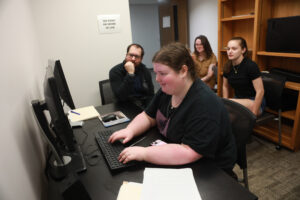 UMW junior Morgan Crabtree (front) crunches data in the Eye Tracking Lab, while Professor of Psychological Science Marcus Leppanen, senior Loren Osborne (middle) and senior Nyah Speicher look on. Photo by Karen Pearlman.