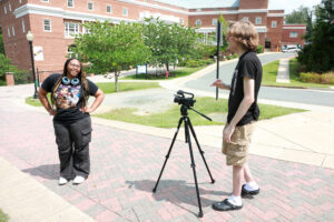 UMW junior Owen Wheeler films Alanah Cleare '25 on Campus Walk. 'Berry Blaster,' the mini-movie they made, was part of their research on AI's usefulness in filmmaking. Photo by Karen Pearlman.