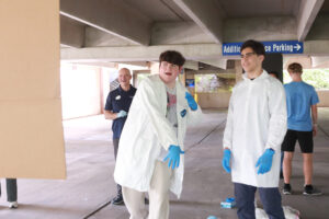 Tristan Towle (center), a junior at Brooke Point High School, chucks a painted cotton ball at the canvas, while Zubair Mohammadzai, a senior at Osbourn Park High School, and UMW Physics Chair and Professor Matt Fleenor watch. Photo by K Pearlman Photography.