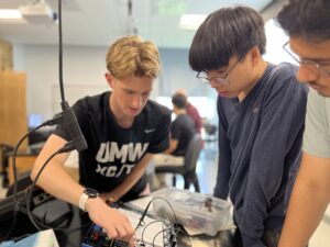 From left: CJ Hulleman ’28, one of the PING program mentors, demonstrates to high schoolers Michael Young and Maiwand Barakzai how to construct a circuit that measures the effect of resonance, a physics concept that can be applied to engineering, biomedicine and technology. Photo by Katie Van Houten ’27.
