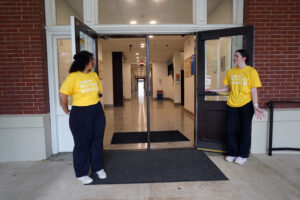 Student Government Association President Amira Said and Vice President Allie Davis hold open the doors of Virginia Hall as they welcome new students on Move-In Day. Photo by Suzanne Carr Rossi.