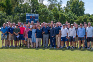 Coach Roy Gordon poses in front of the scoreboard that bears his name, along with his family, friends, former colleagues, UMW Athletics staff and soccer alumni who contributed funding toward field renovations and facilities upgrades on the championship soccer field. Photo by Kaitlynn Kimball.