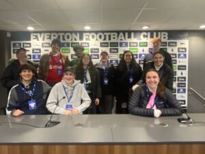 UMW's business of football study-abroad group poses at Everton Football Club's media area with their Professor Dave Henderson during a spring break trip to the U.K. in 2024.