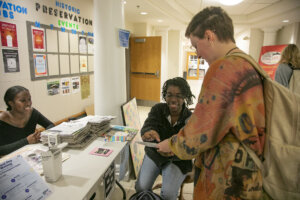 UMW senior Asunta Ross, an English major and president of the English club, gives out stickers for participation in National Day on Writing activities. Photo by Karen Pearlman.