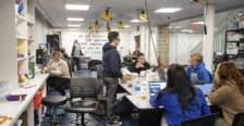 Several students are gathered in a creative space with gadgets and innovative objects galore