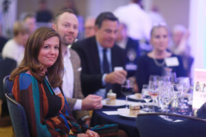 A couple seated at the dinner table listen to President Paino.