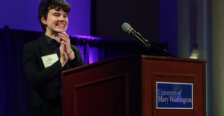 A college student stands at the podium and speaks through the mic.