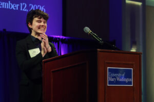 A college student stands at the podium and speaks through the mic.