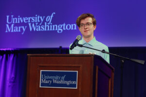 A college student stands at the podium and speaks through the mic.
