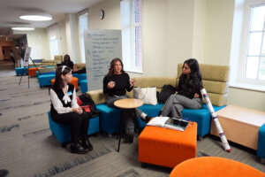 From left: Liberty University students Annaliese DeFelice, a double major in biomedical science and mathematics; and Alyssa Canelo and Victoria Pacheco, both biomedical science majors, rehearse key points of their poster presentation on their research using zebrafish to study the environmental effects of microplastics. They trio was among more than 100 students who shared their scholarly studies at the sixth annual Network for Undergraduate Research in Virginia Conference, held in UMW's Hurley Convergence Center. Photo by Suzanne Carr Rossi.
