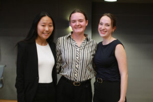 Three smiling students in professional dress.