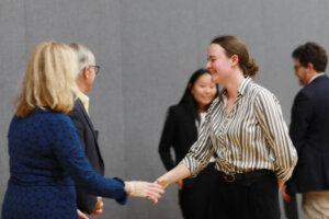 The Mock Interview Competition winner of shakes the hand of a judge, while another judge and finalist look on.