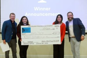 Photo of the two UMW student winners of the 2025 College of Business Fall Case Competition pose with their big check for $1,500 and the two men who created and fund the competition.