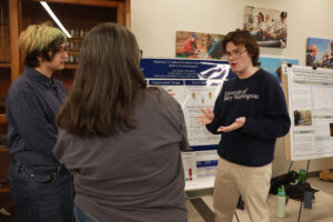 UMW students stand beside a research poster while presenting their work during an end-of-semester symposium.