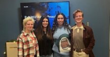 Four student interns, one junior and three seniors, stand together in the University Communications office during a video production showcase.
