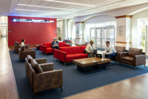 People sit conversing on couches and chairs in a lounge inside UMW's Woodard Hall