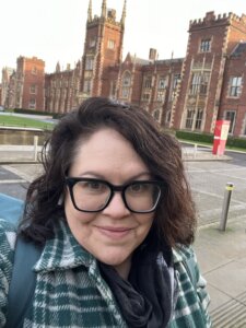 Alumna standing in front of an older building on the campus of Queen's University in Belfast. 