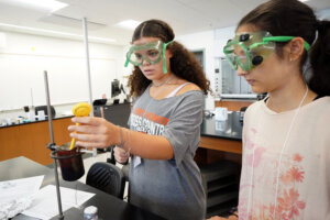 Photo of two students in a science lab performing an experiment